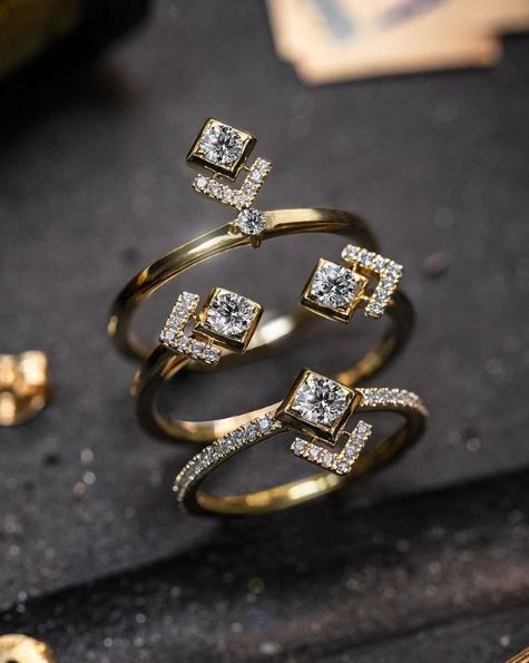 3 row diamond ring with 1 round cut and 4 princess cut diamonds and side pave diamonds on a yellow gold and pave band 