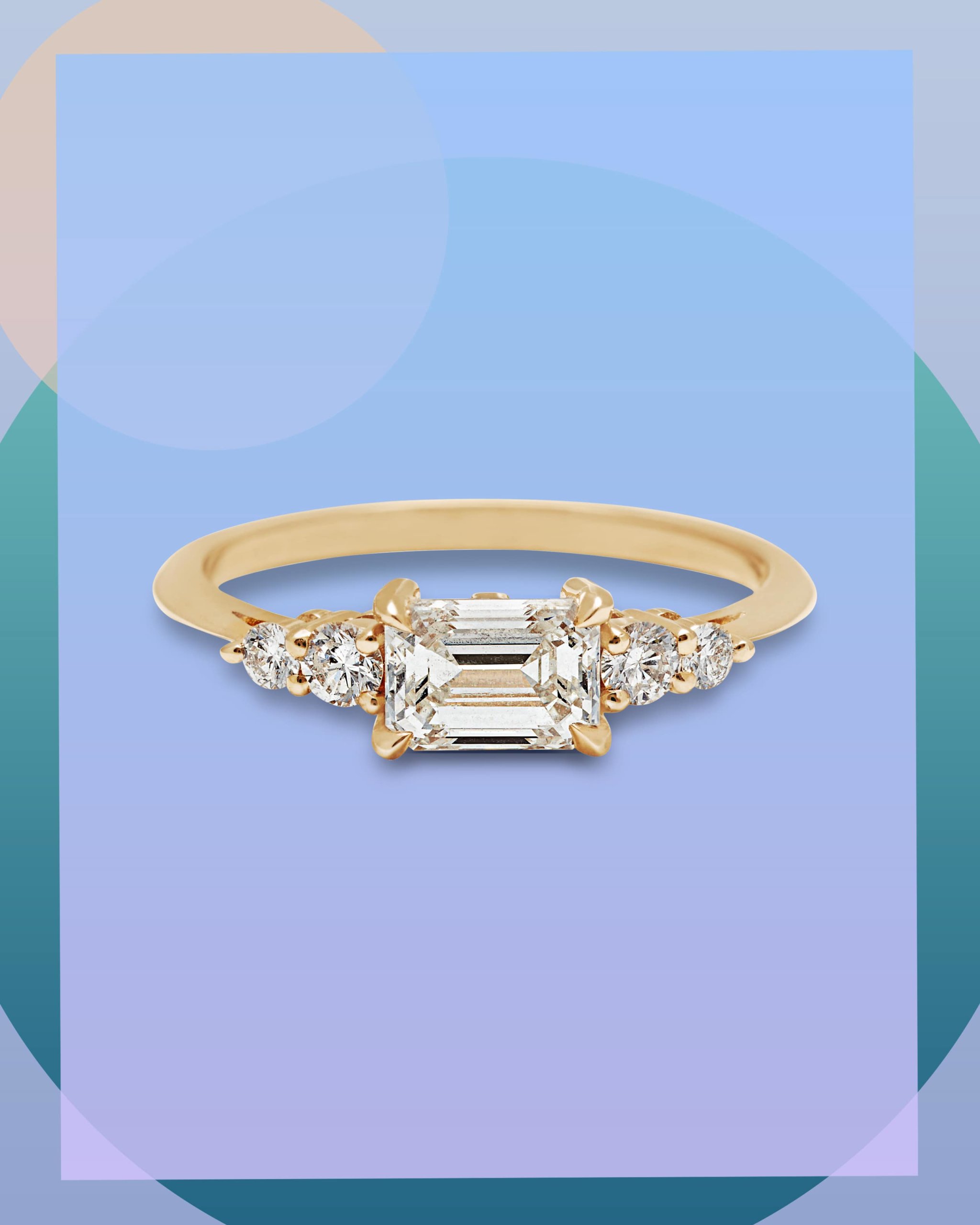 Emerald cut diamond haloed by round cut diamonds in an east west engagement ring with a yellow gold band from Anna Sheffield